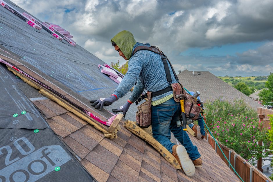 Homeowner reviews a roof warranty beside shingle samples, inspection photos, and a written roofing contract.